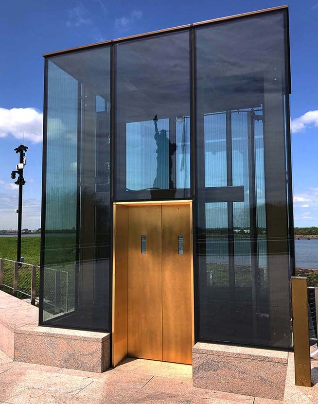 Liberty Island Museum Glass Elevator with copper doors and the reflection of the Statue of Liberty in the glass facade