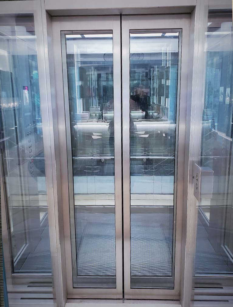 Richard Mille NYC Flagship glass elevator with beveled stainless steel edging along entrance doors