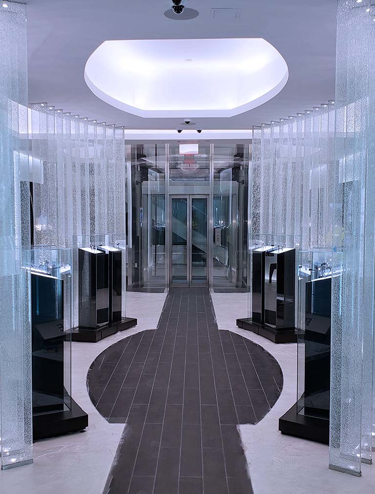 Custom Elevator design with a complete glass enclosure seamlessly integrated into the showroom
