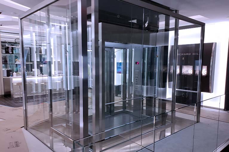 Richard Mille NYC Flagship glass elevator with beveled stainless steel edging on the second floor, rear view